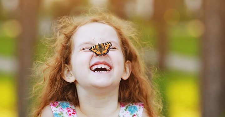 Funny laughing curly girl with a butterfly on his nose. Healthy smile with white teeth. Free breathing concept.