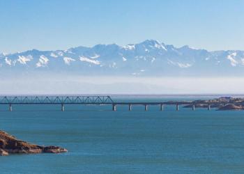 View of the Kapchagay reservoir with islands and a railway bridge against the backdrop of mountains in the Almaty region of Kazakhstan.