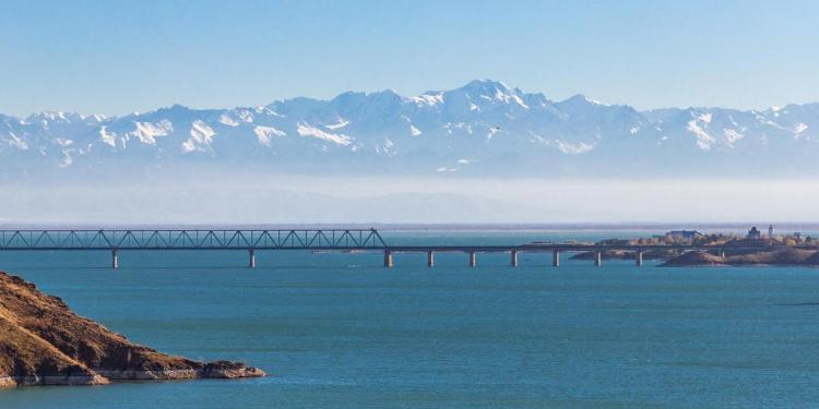 View of the Kapchagay reservoir with islands and a railway bridge against the backdrop of mountains in the Almaty region of Kazakhstan.