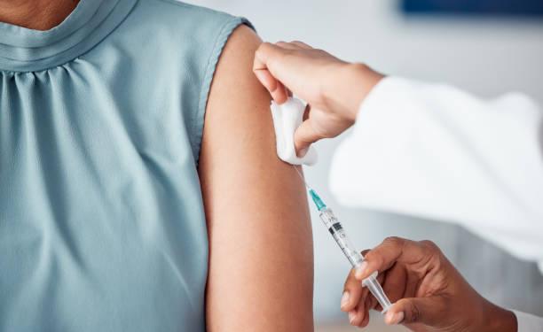 Hands, medical and doctor with patient for vaccine in a clinic for healthcare treatment for prevention. Closeup of a nurse doing a vaccination injection with a needle syringe in a medicare hospital.
